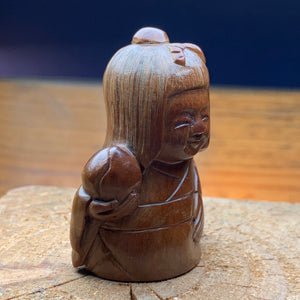Netsuké ningyō en bois représentant une femme avec un fruit.